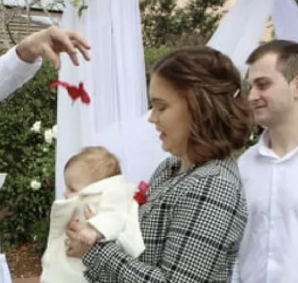Couple holding their baby have red petals sprinkled over them