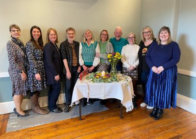 SICA celebrants stand together around a table with a floral display and candle