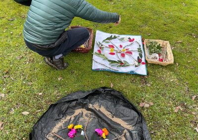 A crouching man scatters petals on a ritual mandala on the grass