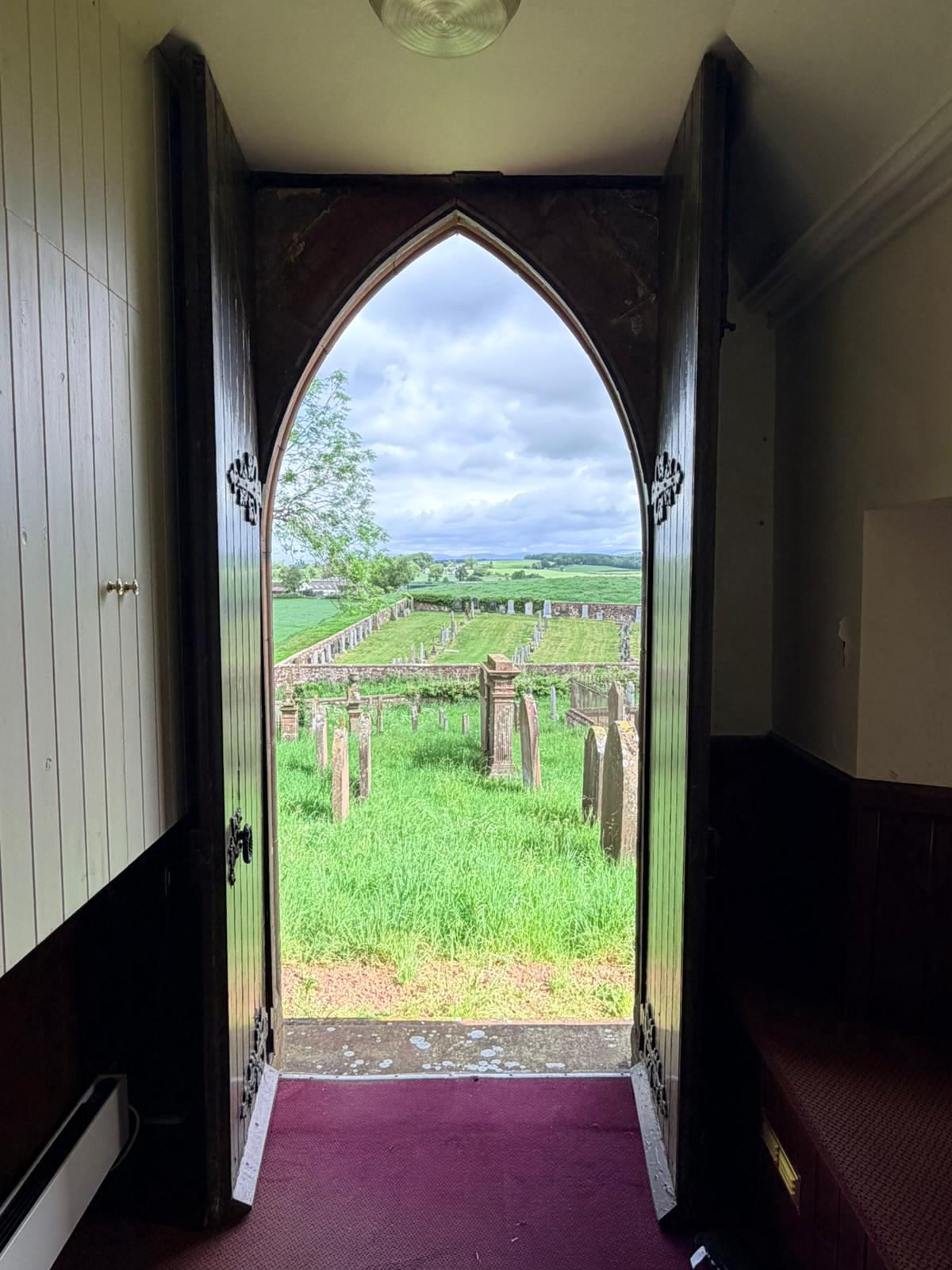 View out of Applegarth Church's door onto the graveyard and fields
